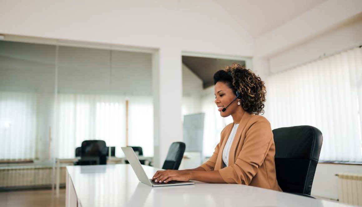 Smiling sales representative talking to client through earpiece. 